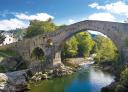 Berühmte römische Brücke in Cangas de Onís über einen kristallklaren Fluss in einer grünen Landschaft mit dem Siegeskreuz.