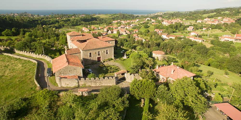 Paisagem das Astúrias mostrando o Palácio de Gobiendes e a aldeia vizinha, num ambiente rural com vista para o mar.