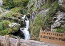 Cartel de bienvenida a Las Foces del Pino junto a una cascada en la montaña