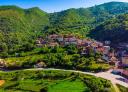 Aerial view of an Asturian village in a green valley surrounded by lush mountains.