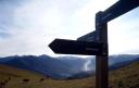Señal de madera con indicaciones de rutas en un paisaje montañoso asturiano
