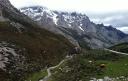Valle montañoso con un sendero serpenteante y cumbres nevadas al fondo