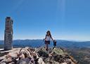 A person standing next to a stone cairn at the summit.