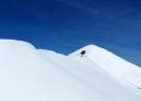 Snow-capped ridge of a mountain range with blue sky in the background