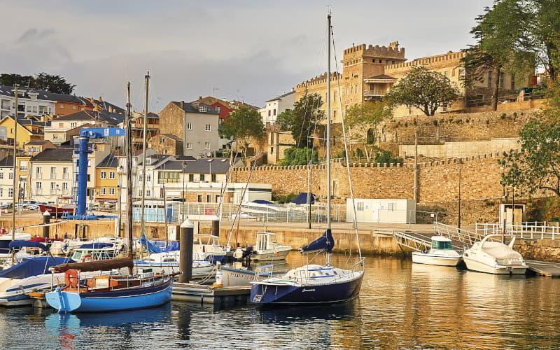 Bateaux amarrés dans le port de Figueras, à Castropol, avec le palais de la famille Pardo Donlebún et les maisons du centre ville dominant le quai.