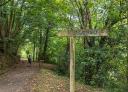 Senderistas caminando por la Senda Verde de Lloreo junto a un cartel del paraje de Frechura.