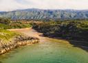 Aerial view of Poo beach with mountains in the background.