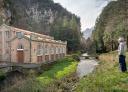 Un senderista observa desde la orilla del río la Central Hidráulica del La Malva