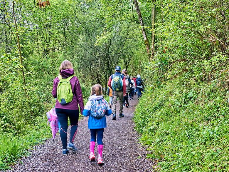 Grupo de personas caminando por la ruta de La Peridiella en Piloña entre vegetación