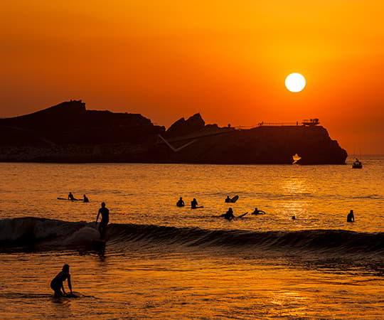 Atardecer en la playa de Salinas con unos surfistas en primer plano