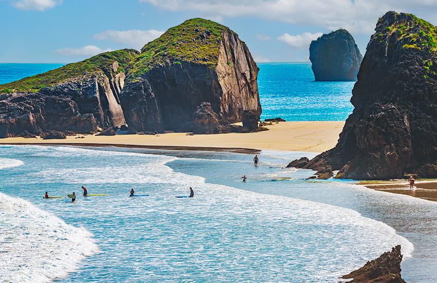 Surfistas detro del agua en la playa de San Martín en llanes esperando las olas.