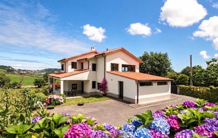 Vista exterior de la casa con jardín y hortensias.