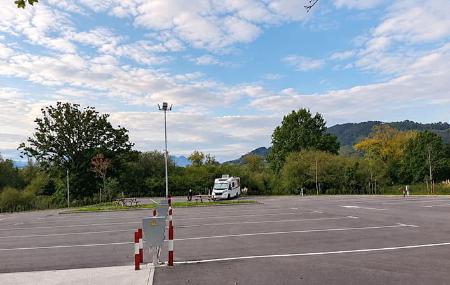 Vista panorámica de las plazas de estacionamiento del área de autocaravanas de Lugones, con zonas verdes al fondo.