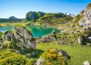 Vista del lago Enol entre formaciones rocosas y praderas de montaña en los Lagos de Covadonga.