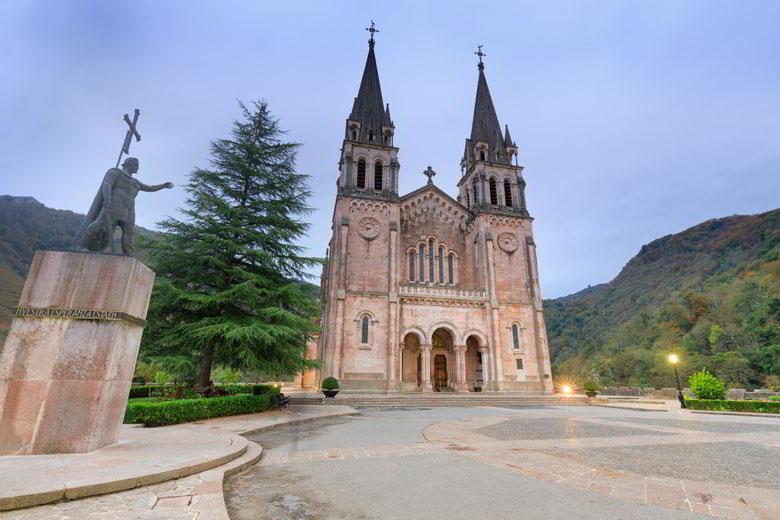 Die Statue von König Pelayo auf der linken Seite und die Fassade der Basilika von Covadonga im Vordergund.