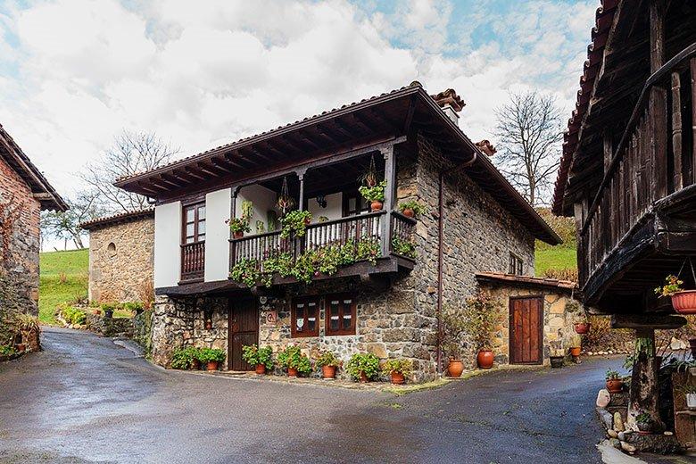 Photo de l'extérieur du gîte rural Caserío de San Pedro (de la marque Aldeas de Asturias) dans la commune de Llanes. Au premier plan, une maison et un horreo.