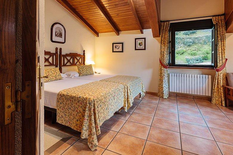 Foto de una habitación de dos camas con vistas al jardín de la casa rural el Llugarón III (de la marca Aldeas de Asturias) en el concejo de Villaviciosa.