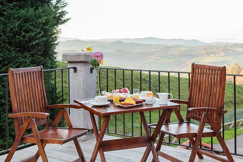 Foto de la terraza con una mesa con el desayuno preparado en la casa rural Manuel de Pepa Xuaca (de la marca Aldeas de Asturias) en el concejo de Langreo.