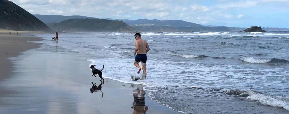 Imagen de una persona con su perro por la playa.
